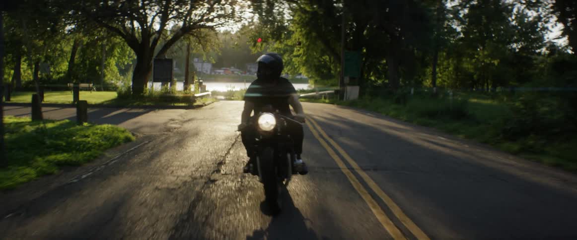 A motorcycle turns onto a road and drives forward