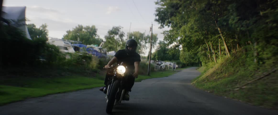 A motorcyclist rides on a narrow road