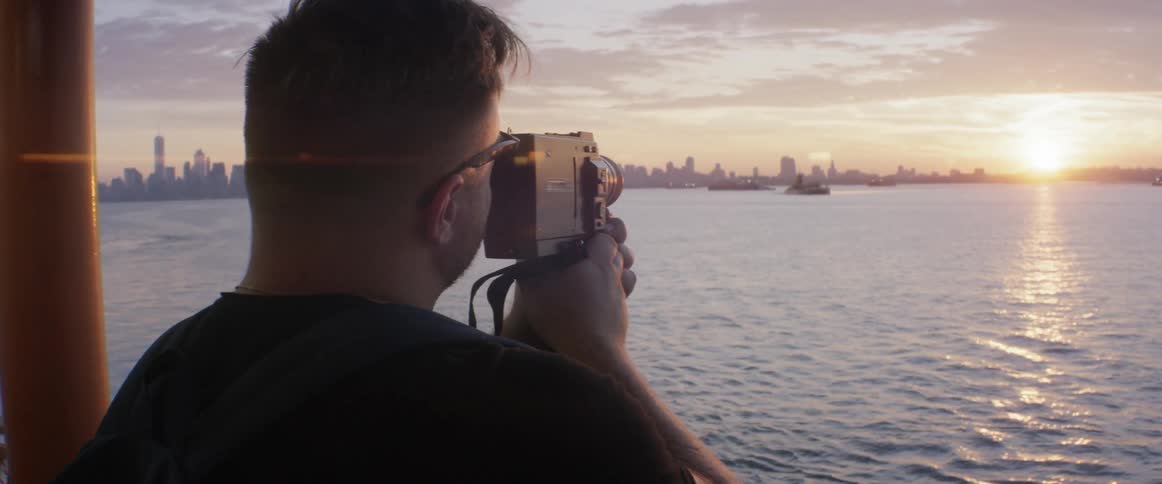 A man videos a city skyline from a boat