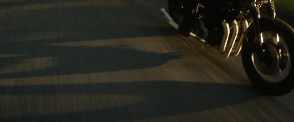 A motorcyclist rides down a road in a rural area