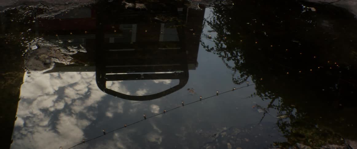 Sky and building reflected in a puddle of water