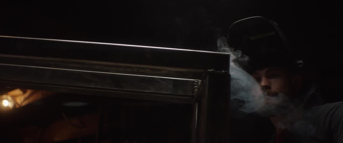 A person is welding some metal in a dark area