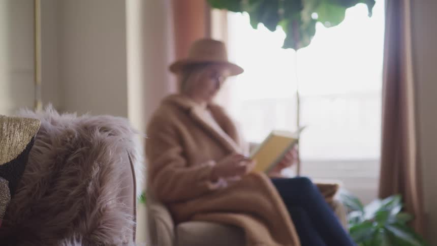 A woman sitting at home reading a book