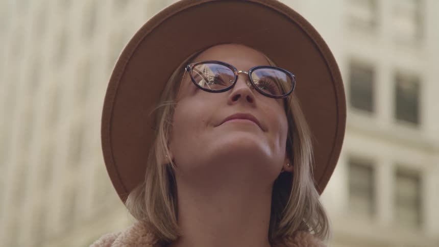A woman stands outside and looks up at the buildings in a city
