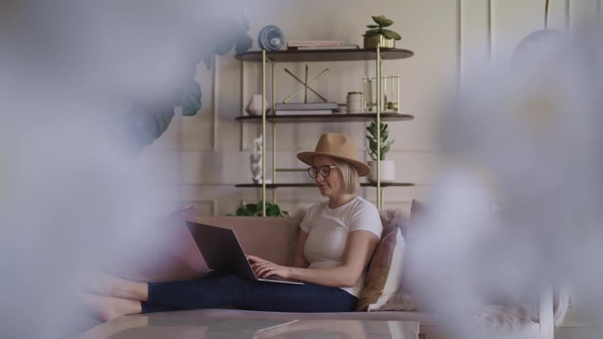 A woman is indoors and typing on a laptop