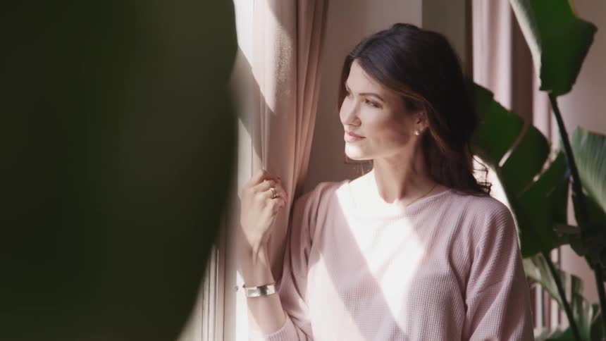 Pretty smiling asian woman posing next to a sunlit window indoors