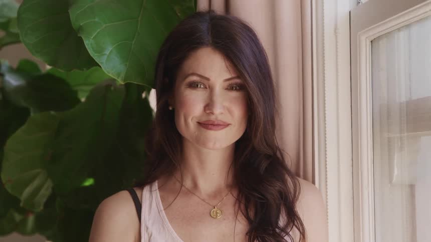 A woman at home turns and smiles for a portrait