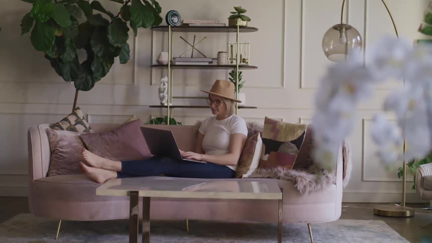 A woman is sitting on a couch typing on a laptop