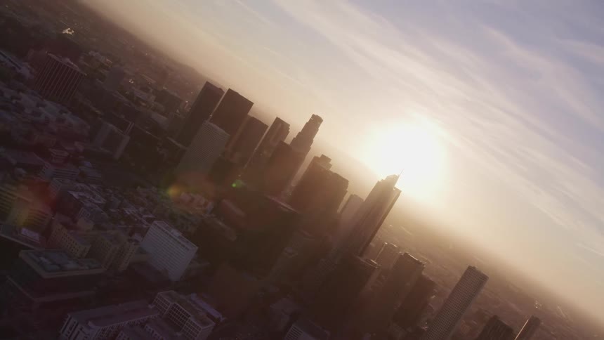 The sun shining behind silhouetted skyscrapers in a large city