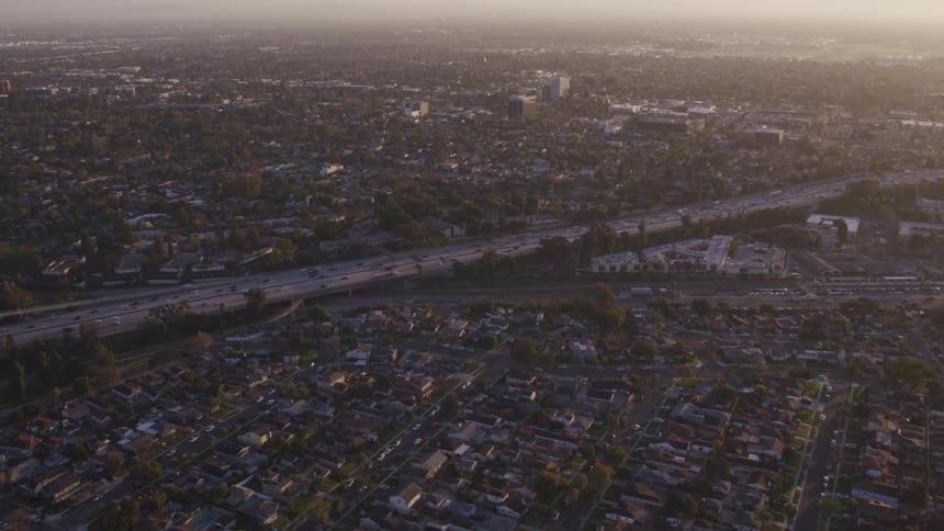 Traffic is steady on a highway running past dense city neighborhood