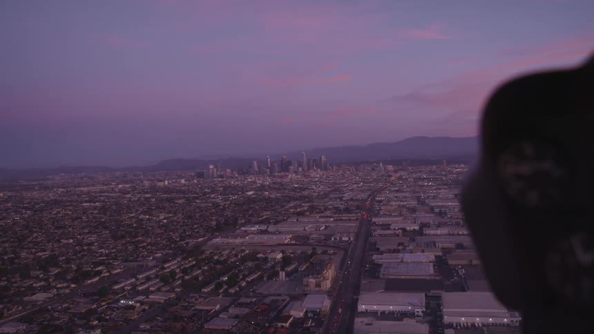 A city skyline with cars driving on the road as seen from an airplane