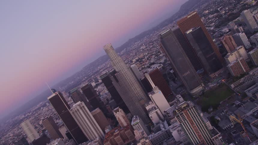 Aerial view of city skyline with tall buildings and skyscrapers at sunset