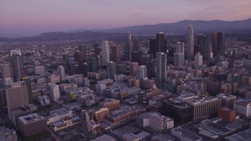Aerial view of city skyline with tall buildings and skyscrapers at sunset