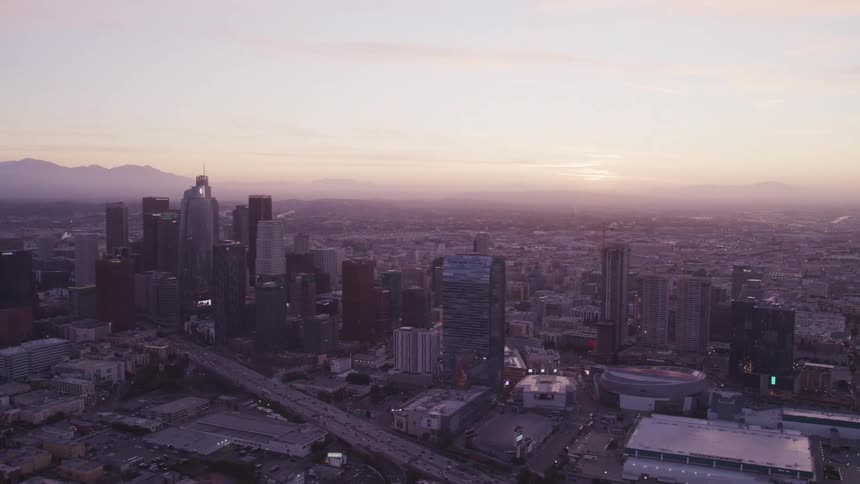 An aerial view of a downtown city is displayed at sunset