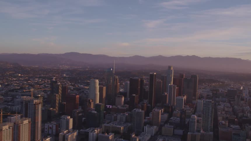 Aerial view of city skyline with tall buildings and skyscrapers at sunset