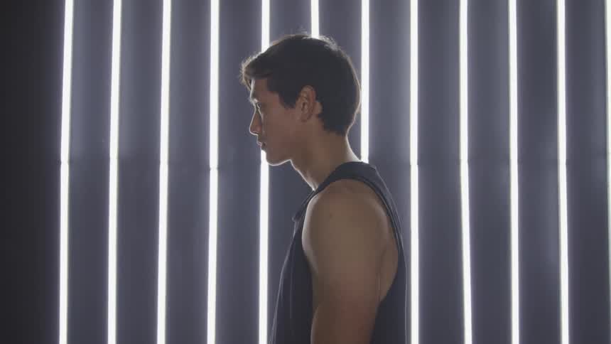 Man standing in profile in front of window looks up from floor