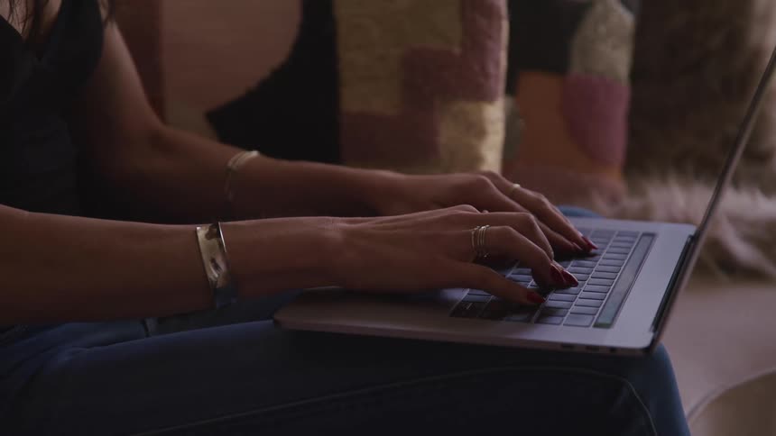 A woman is typing on a laptop