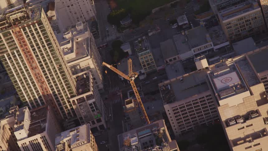 Aerial view of a construction crane in the middle of the city at sunset