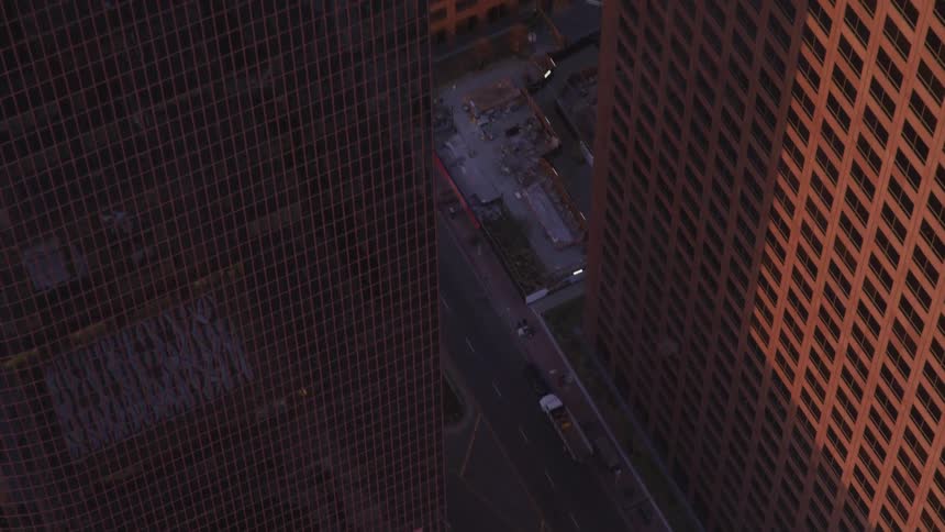 A wide street surrounded by skyscrapers in a metropolis in the evening