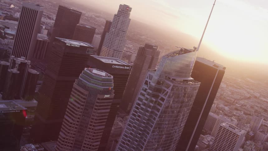Aerial view of city skyline with tall buildings and skyscrapers at sunset