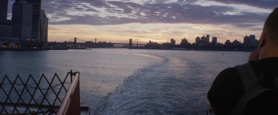 View from the back of a boat of a city as the sun sets