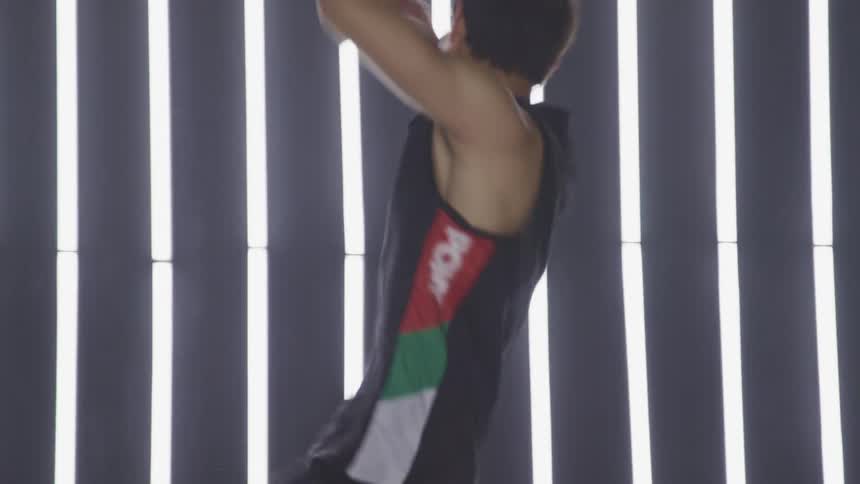 A man with a tank top dancing on stage with lights in the background