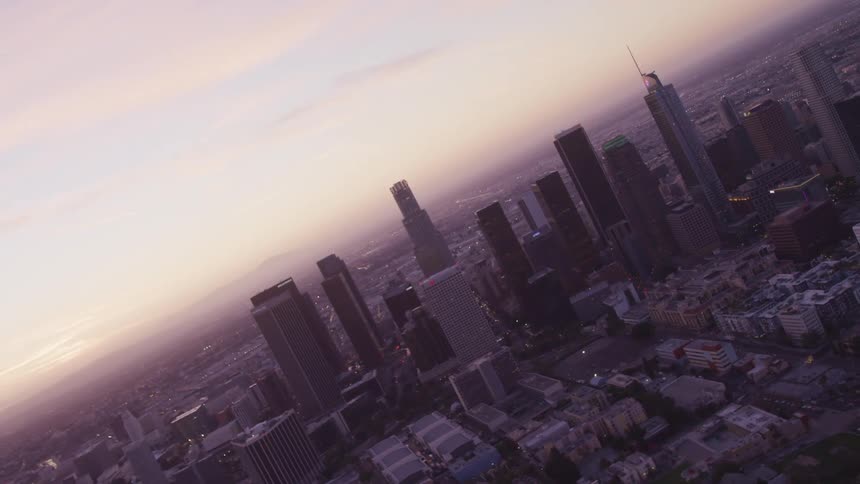 Aerial view of city skyline with tall buildings and skyscrapers at sunset