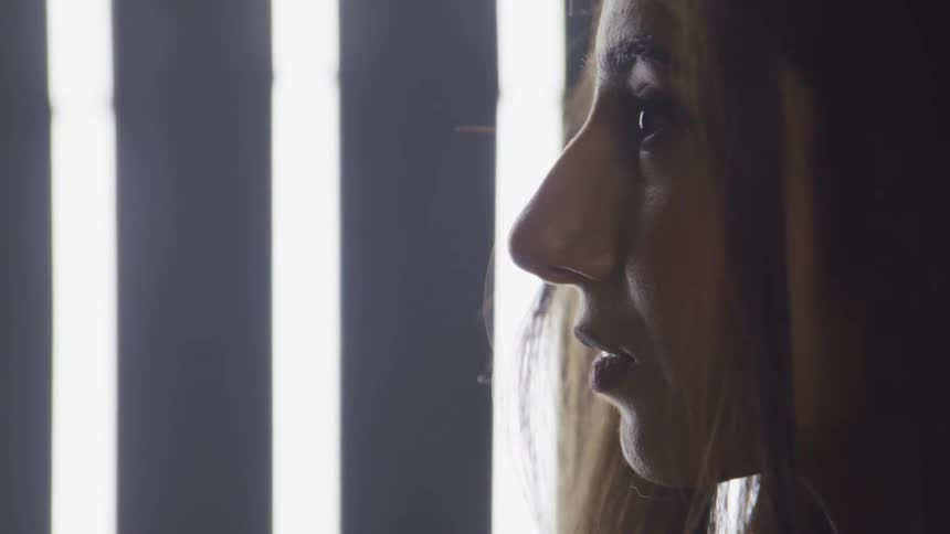 A woman stands in profile in front of a lighted wall