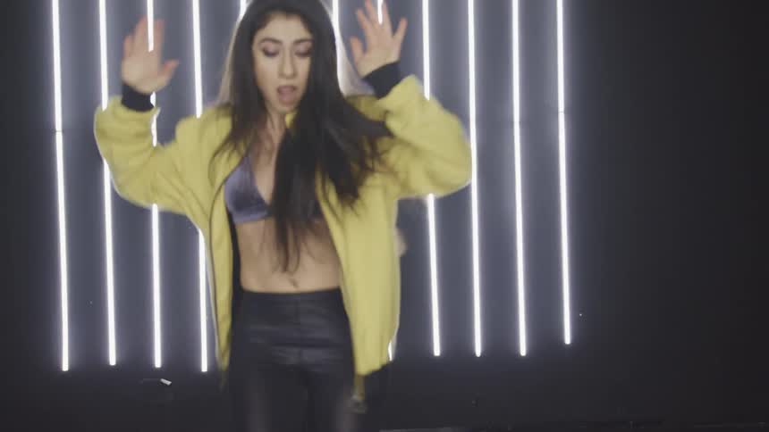 A young woman dancing in front of bright lights