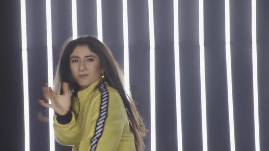 A woman dances hip hop in front of a lighted area