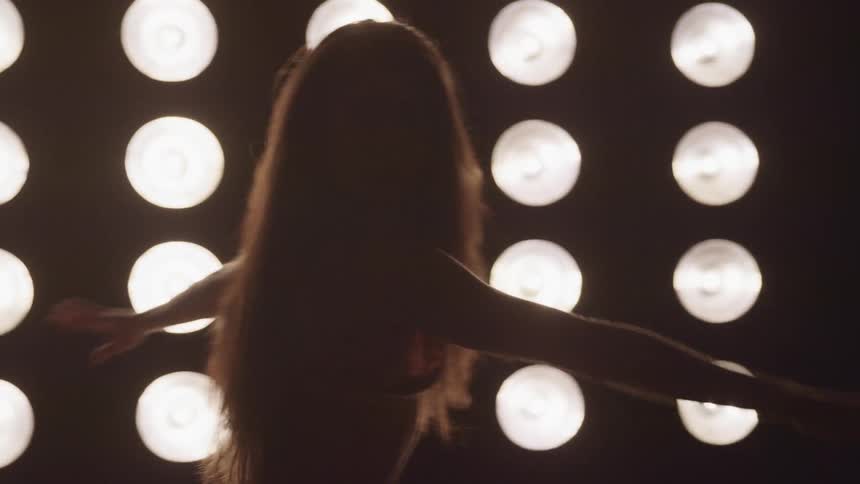 A woman is dancing in front of many lights