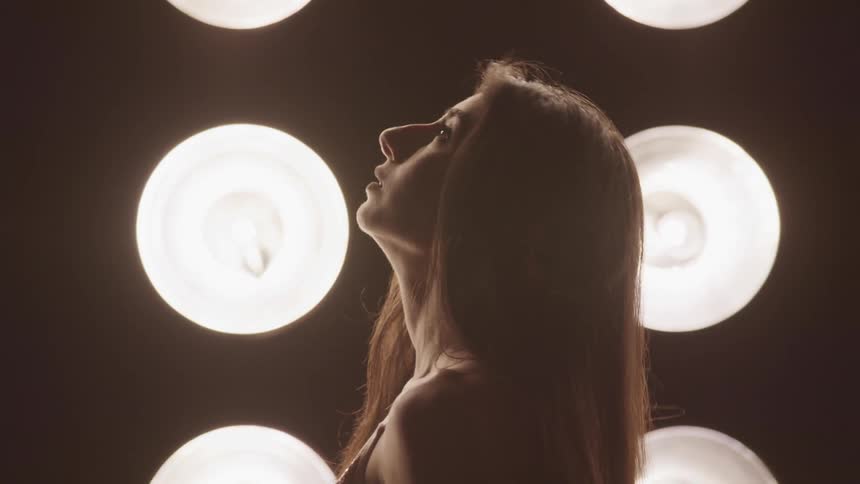 A woman looking up in front of lights with light bulbs