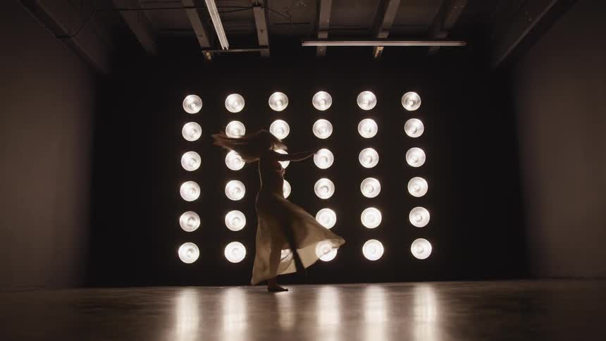 A woman is dancing in front of the lights