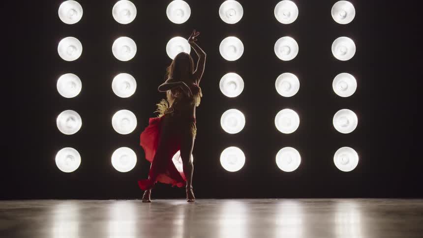 A woman with a dress dancing on a stage with lights in the background