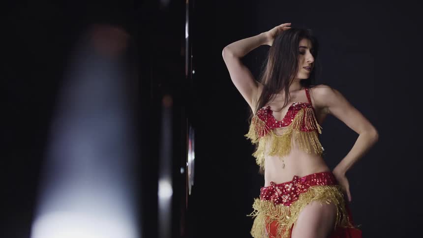 A woman on stage belly dancing with lights next to her