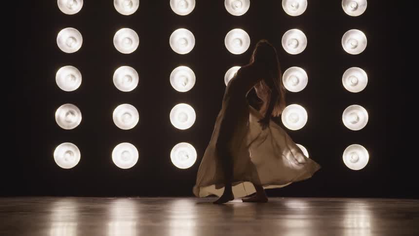 Silhouette of a woman in a dress dancing on the stage