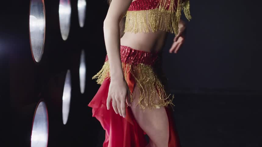 Belly dancer performs a dance moving her hips and stomach in the studio