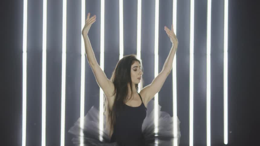 Ballerina wearing a black tutu dances ballet on stage
