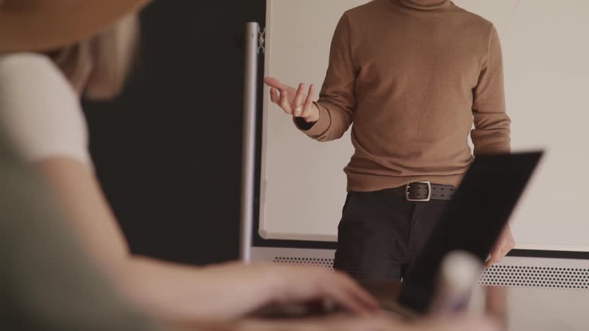 A male gesturing to a female who is sitting down at a desk