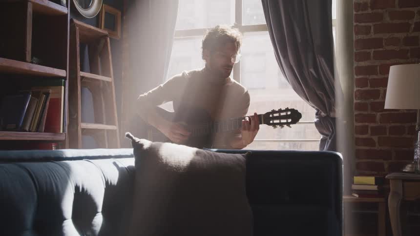 A man is playing the guitar in a room
