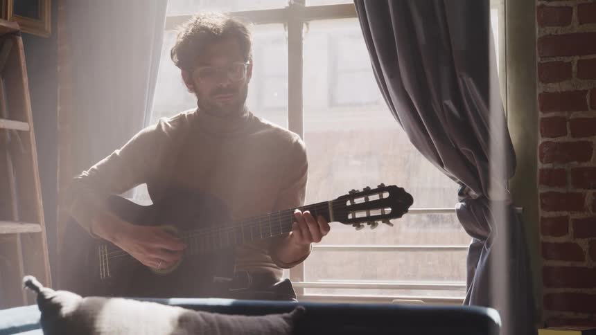 A man plays a guitar in his home
