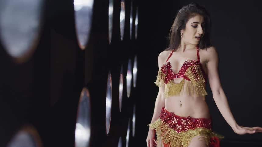A young woman in glittering clothing dances in front of a tall array of lights