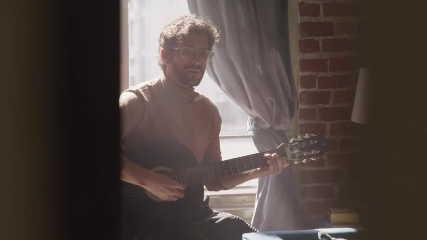 A man is playing guitar in a room