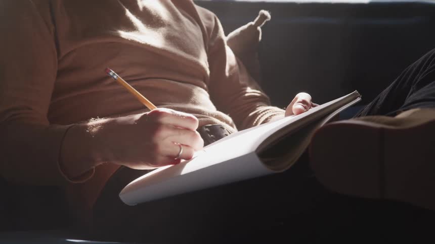 A man is sitting on a couch and writing