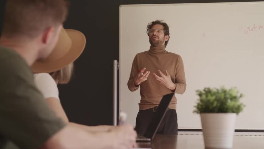A male professor gives a lecture to students in a college classroom