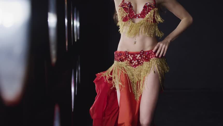 Belly dancer moves her belly and hips around in studio