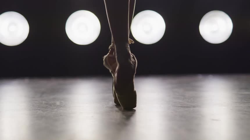 Close up of a woman foots while dancing classical ballet on stage