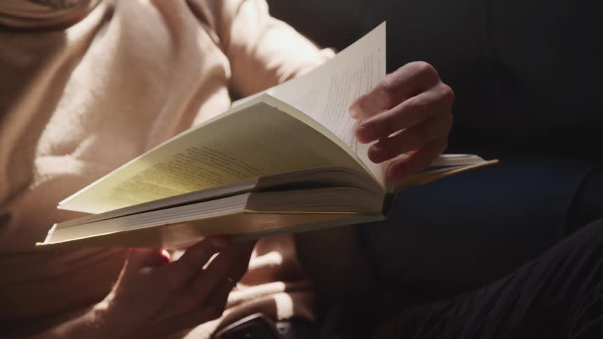 Man with a brown turtleneck sweater reads a book