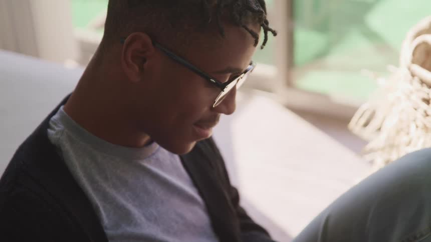 Side view of a black man with glasses looking down and smiling slightly