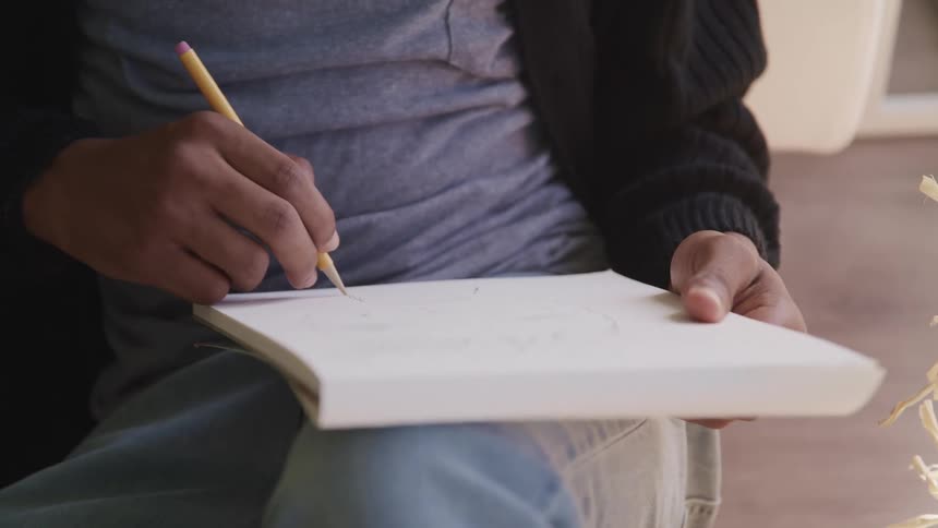 A person is sitting on a chair and writing on a piece of paper